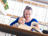 Eine studierende Mutter liest mit Baby auf dem Schoß in der Zentralbibliothek. Foto: Universität Passau/Studentenwerk Niederbayern/Oberpfalz