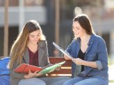 Zwei Studierende sitzen auf einer Bank und lernen gemeinsam.